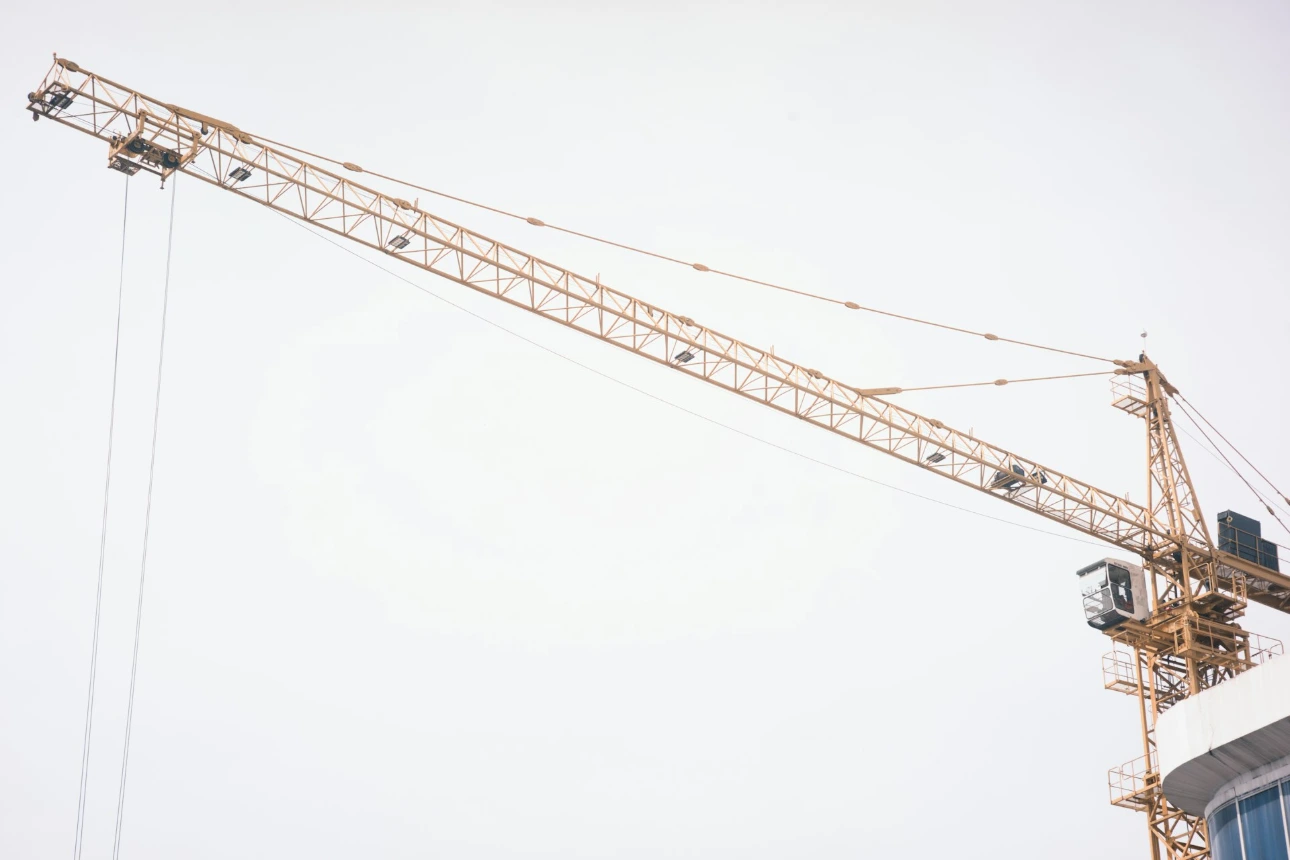 A yellow construction crane against a white sky